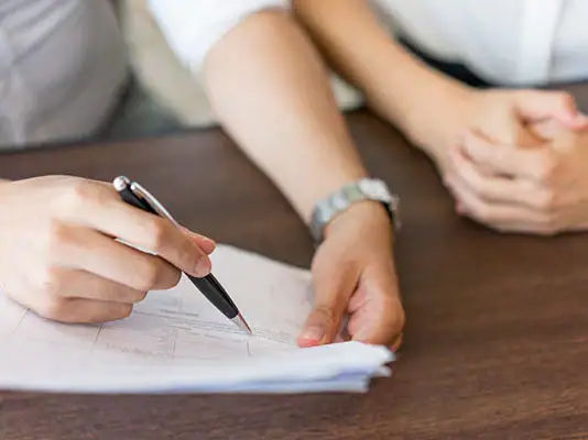 Person signing paperwork during medical marijuana consultation at B & B Medical Center.